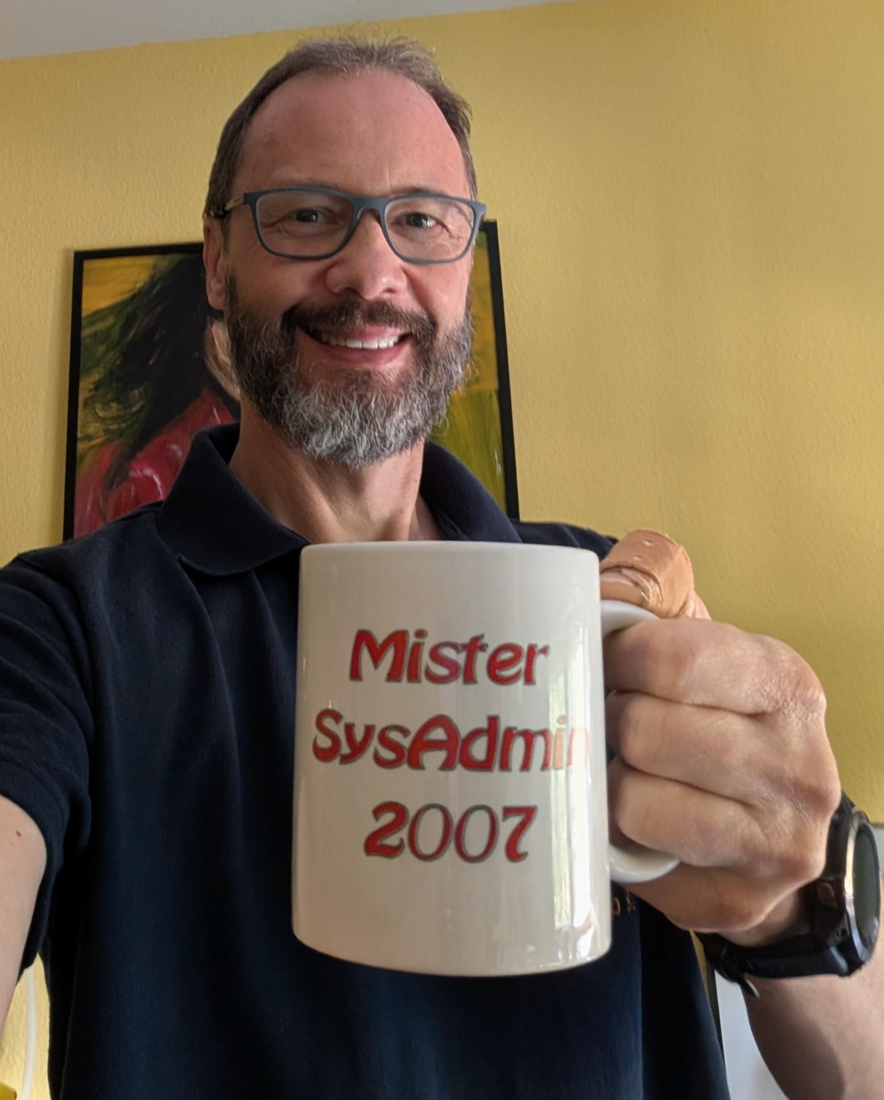 Michael mit einer Kaffeetasse in der Hand, mit der Aufschrift "Mister Sysadmin 2007".