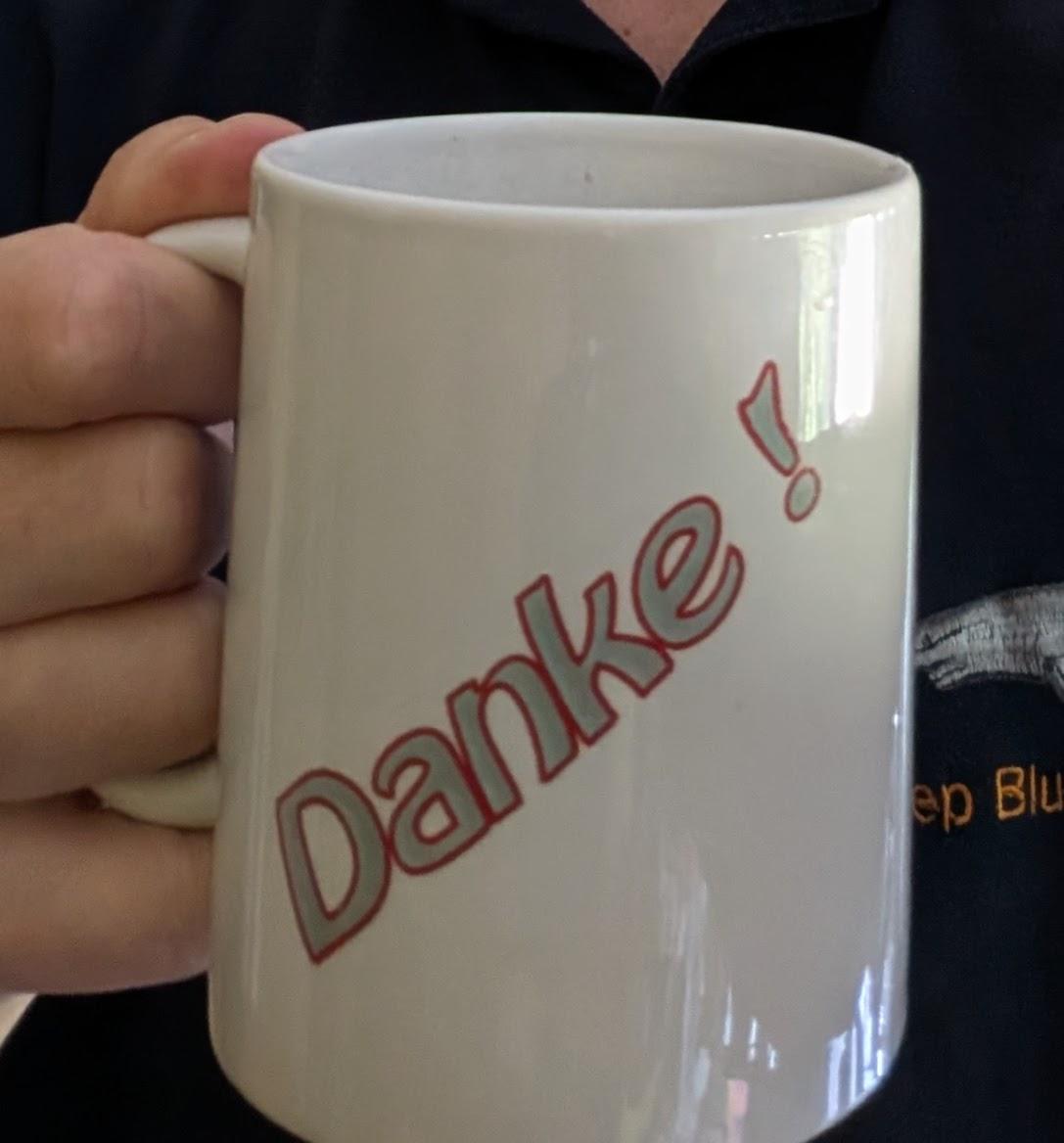 Die andere Seite der gleichen weißen Kaffeetasse, Aufschrift "Danke !"